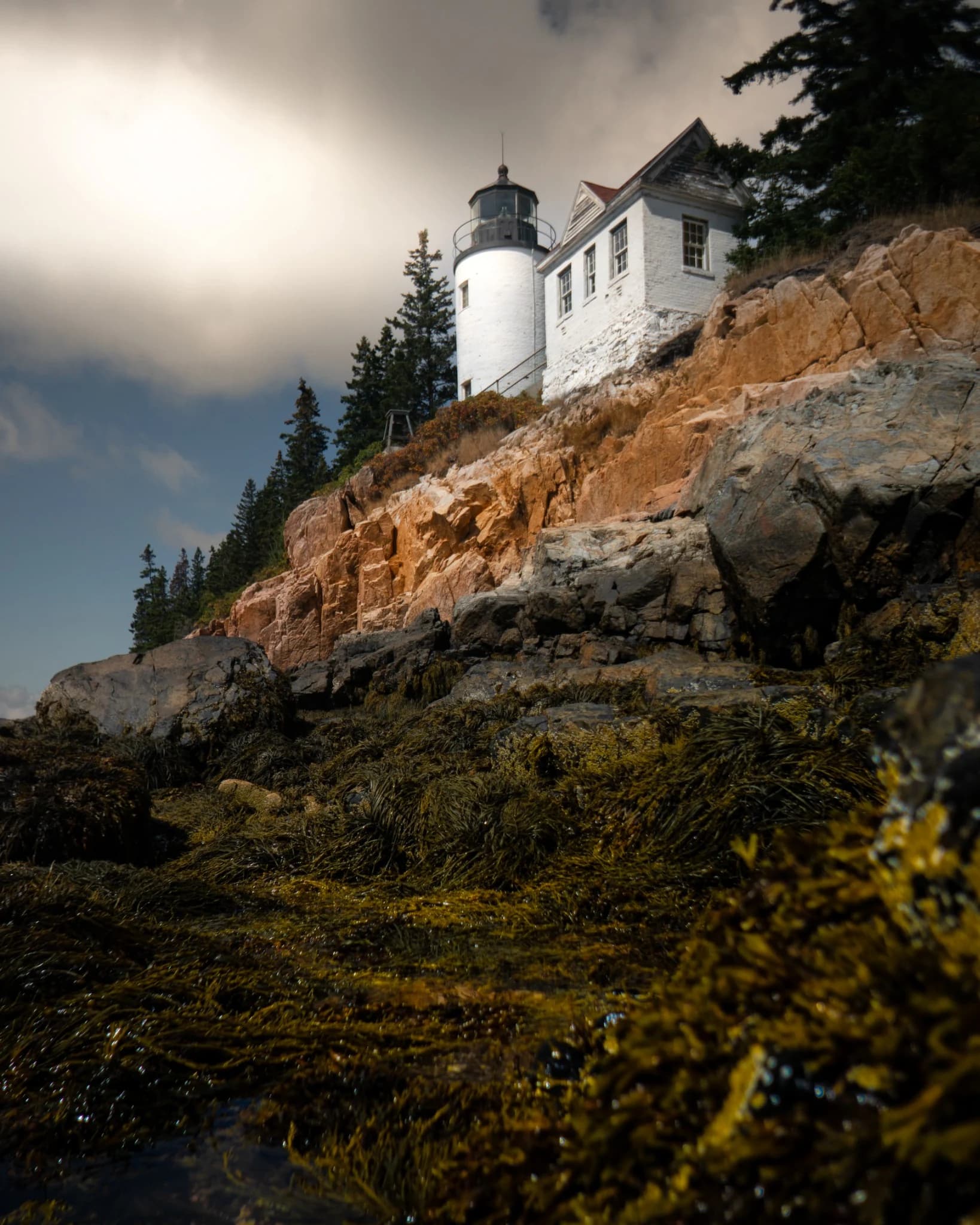 White lighthouse above a rugged rocky Maine shoreline